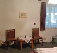 Pokoj v rodinném domě s dřevěným stropem, dvěma židlemi a stolkem.