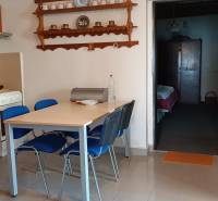 Jídelna rodinného domu s policemi na nádobí a stolem s modrými židlemi.