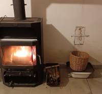 Krbová kamna v rodinném domě, vedle kterých jsou košíky s dřevem a ovocem.