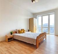 Ložnice v 2-pokojovém bytě s podlahou s dřevěným dekorem a velkými okny.