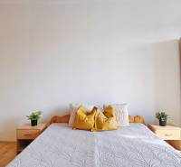 Ložnice s dřevěnými skříněmi a postelí v 2pokojovém bytě, podlaha s dřevěným dekorem.