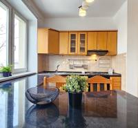 Kuchyně s dřevěnými skříňkami a černou pracovní deskou v 2-pokojovém bytě.