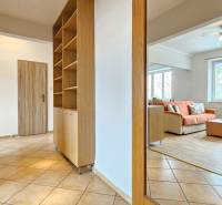 Chodba v 2-pokojovém bytě s dlažbou, vestavěnou skříní a výhledem do obývacího pokoje.