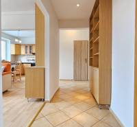 Chodba v 2-pokojovém bytě s podlahou s dřevěným dekorem a kuchyní v pozadí.
