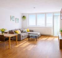 Obývací pokoj v 2-pokojovém bytě s rohovou pohovkou a podlahou s dřevěným dekorem.