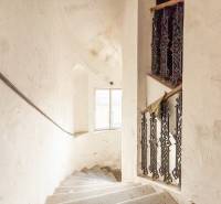 Schodiště v rodinném domě s oknem a ozdobným zábradlím, bílá stěna s patinou.