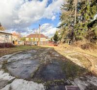 Rodinný dům v obci Bobot, na ulici Bobot, s betonovou plochou a dřevinami v zahradě.