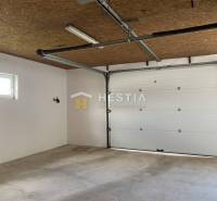 Interiér skladů a hal s garážovými vraty a betonovou podlahou.