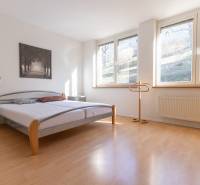 Světlá ložnice s postelí a podlahou s dřevěným dekorem ve 3-pokojovém bytě.