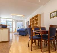 Obývací pokoj s podlahou s dřevěným dekorem, jídelním stolem a pračkou ve 3pokojovém bytě.