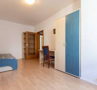 Pokoj v 3-pokojovém bytě s podlahou s dřevěným dekorem, skříní a pohovkou.