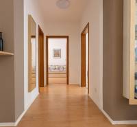 Chodba ve 3-pokojovém bytě s podlahou s dřevěným dekorem, zrcadlem a skleněnou vitrínou.