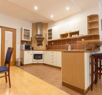 Kuchyně ve 3-pokojovém bytě s podlahou s dřevěným dekorem a barovým pultem.