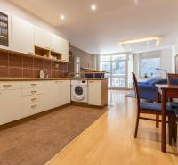 Kuchyně s podlahou s dřevěným dekorem, pračkou a jídelním stolem ve 3-pokojovém bytě.