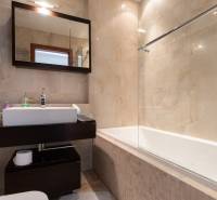 Koupelna s vanou a tmavým nábytkem v 2pokojovém bytě, světlé obklady.