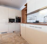 Kuchyně v 2-pokojovém bytě s bílými skříňkami a spotřebiči.