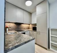 Kuchyně v 2pokojovém bytě s kamennou pracovní deskou a bílými skříňkami.