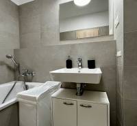 Koupelna s vanou a umyvadlem v 2pokojovém bytě s keramickými obklady.