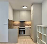 Kuchyně v 2-pokojovém bytě s podlahou s dřevěným dekorem a úložnými policemi.