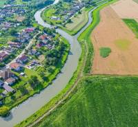 Řeka tekoucí podél zemědělských a lesních pozemků v Černé Vodě, vedle obce.