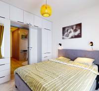 Ložnice v 3pokojovém bytě s pohodlnou postelí, vestavěnou skříní a podlahou s dřevěným dekorem.