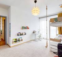 Dětský pokoj ve 3-pokojovém bytě s postelí, stolkem a kytarou.