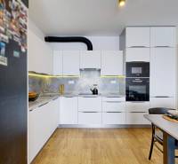 Kuchyně ve 3-pokojovém bytě s bílými skříňkami a podlahou s dřevěným dekorem.