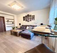 Obývací pokoj v 2-pokojovém bytě s pohovkou, dekoracemi a podlahou s dřevěným dekorem.