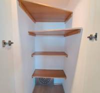 Šatník s vestavěnými policemi ve 4pokojovém bytě s podlahou s dřevěným dekorem.