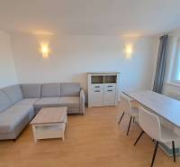 Obývací pokoj ve 4pokojovém bytě s rohovou sedačkou a jídelním stolem.