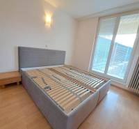 Ložnice ve 4pokojovém bytě s postelí a nočním stolkem, podlaha s dřevěným dekorem.