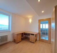 Pracovna ve 4-pokojovém bytě s podlahou s dřevěným dekorem a psacím stolem.