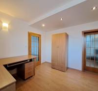 Pokoj ve 4pokojovém bytě s podlahou s dřevěným dekorem, stolem a skříní.