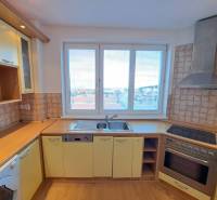 Kuchyně ve 4pokojovém bytě s podlahou s dřevěným dekorem a výhledem na město.