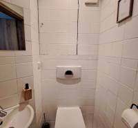 Koupelna se standardní bílou dlažbou a umyvadlem ve 4-pokojovém bytě.