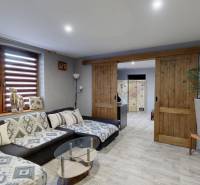 Obývací pokoj s pohodlnou sedačkou, posuvnými dveřmi a podlahou s dřevěným dekorem.