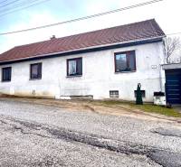 Rodinný dům v Unínu s bílou fasádou, hnědou střechou a přístupovou cestou.