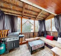 V rodinném domě je krytá terasa s grilem, závětřím a zahradním nábytkem.