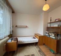 Pokoj v rodinném domě s postelí, poličkami a podlahou s dřevěným dekorem.