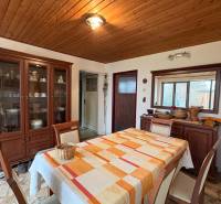 Jídelna v rodinném domě se stolem, židlemi a skříní, podlaha s dřevěným dekorem.