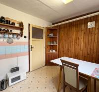 Kuchyňský kout v rodinném domě s dřevěným obkladem a retro vybavením.