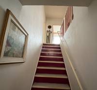 Schodiště v rodinném domě s obrazem na stěně.