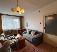 Obývací pokoj v rodinném domě s pohovkou, stolem a retro lustrem.