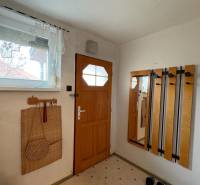 Vstupní hala rodinného domu s dřevěnými dveřmi a praktickým věšákovým systémem.