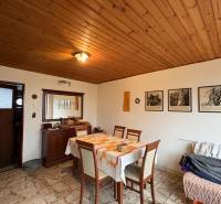 Jídelna rodinného domu s dřevěným stropem a dekorativními obrazy na stěně.