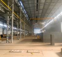 Výrobní prostory s kovovými konstrukcemi a jeřábem uvnitř haly.