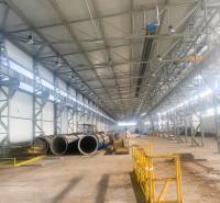 Výrobní prostory s kovovými konstrukcemi a potrubím, Dobšiná. Široká hala se žlutými zábranami.