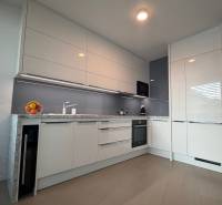 Moderní kuchyně v 2pokojovém bytě s podlahou s dřevěným dekorem a bílými skříňkami.