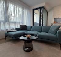 Obývací pokoj s pohovkou, stolkem a kuchyňským koutem v 2-pokojovém bytě.