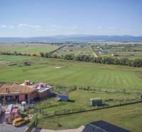 Pozemky - bydlení v Mlynici s výhledem na rozestavěnou budovu a scenérii přírody.